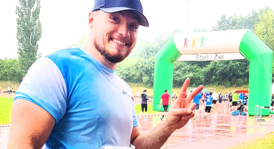 News Hand in Hand Charity Run Runner with AFI Shirt posing infront of Finishline